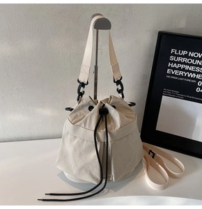 Detail van beige canvas emmer tas met trekkoord sluiting en zwarte haken op een display standaard