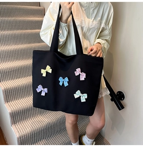 Detail of a black canvas tote bag featuring five colorful polka dot bow decorations