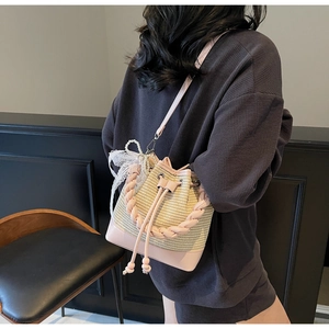 Detail of pink and beige woven straw bucket bag with lace bow and pearl charm