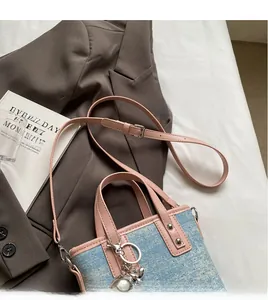 Detail of adjustable pink leather strap and silver rivet on blue denim bucket bag