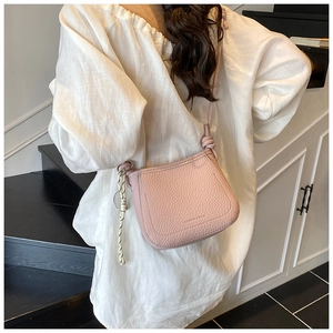 Pink lychee grain crossbody bucket bag detail with knotted strap and tassel decor