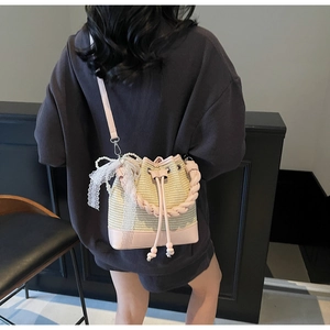 Detail of straw bucket bag with pink leather trim, lace bow, and pearl embellishments