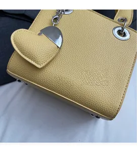 Close-up of yellow lychee pattern leather handbag with silver buckles and heart charm