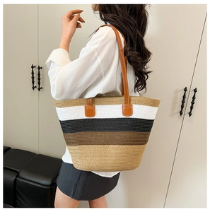 Detalle del bolso de hombro de paja trenzada con rayas multicolores llevado por una modelo