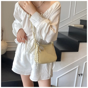 Detail of light beige bucket bag with pebble leather texture and braided rope strap