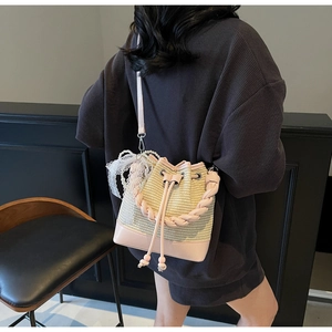 Detail of hand-woven straw bucket bag with pink leather trim and white lace bow decoration