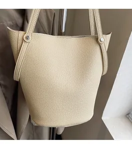 Close-up of off-white lychee pattern leather bucket bag with silver metal rivets details