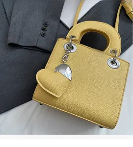 Detail of yellow pebbled leather handbag with sturdy handles and heart-shaped charm