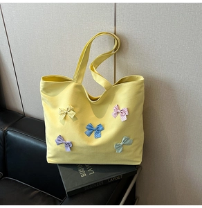 Detail of yellow canvas tote bag with grid texture and five colorful decorative bows