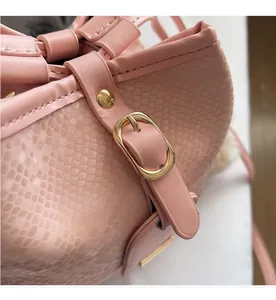 Detail shot of pink embossed leather bucket bag with premium gold buckle and rivet hardware