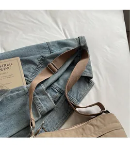 Close-up of adjustable wide fabric shoulder strap and metal buckle on khaki tote bag