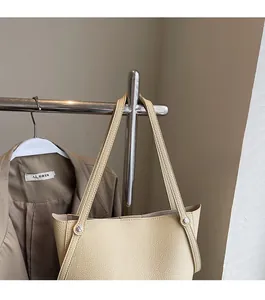 Close-up of beige lychee grain leather shoulder bag with silver rivet details