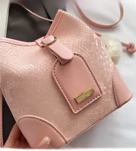Detail of pink snakeskin bucket bag featuring a soft faux leather texture and plush ball charm