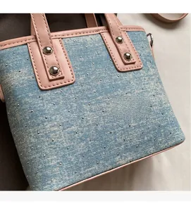 Close-up of blue denim handbag with silver studs and pink leather strap detailing