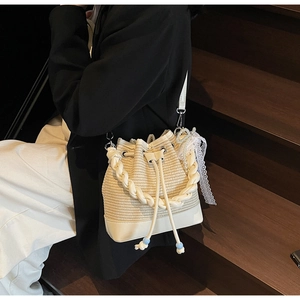 Detail of woven straw bucket bag with white leather trim and pearl lace charm
