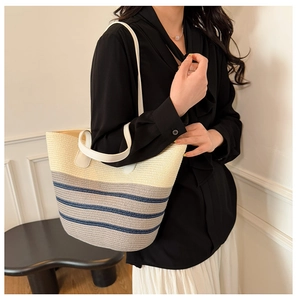 Detalle de bolso tote de paja tejida con rayas de colores y asas de PU blanco