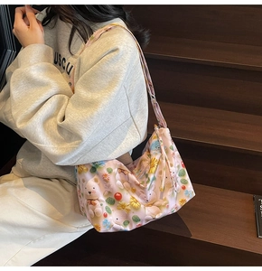 Detail of pink cartoon tote bag with floral bear pattern shown on wooden stairs