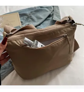 Detailed view of khaki nylon crossbody bag with multi-layer zippers and woven shoulder strap