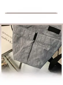 Dettaglio della borsa in nylon grigio stropicciato con trama resistente e logo nero