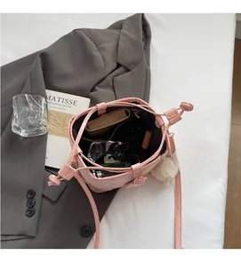 Detail view showing spacious interior pockets of pink bucket bag with various accessories