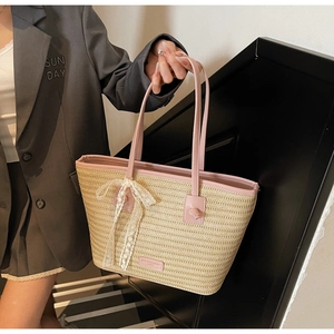 Détail du sac fourre-tout en paille tissée avec anses roses et nœud en dentelle blanche