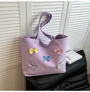 Close-up of purple canvas tote bag featuring colorful bow decorations and grid texture
