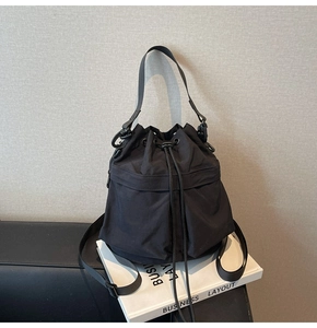 Detail van zwarte nylon emmertas met trekkoordsluiting en stevig handvat aan de bovenkant