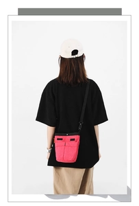 Dettaglio borsa a tracolla in nylon rosa con design multitasche e cinturino regolabile
