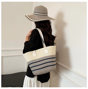 Detalle del bolso tote de paja tejida con rayas azules y sombrero de sol a juego