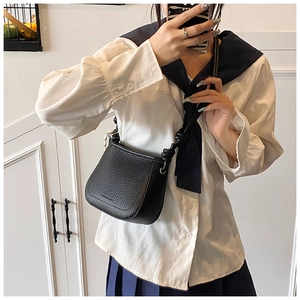 Close-up of black lychee-grain leather bucket bag with flap and knot strap detail