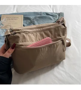 Detail showing khaki nylon crossbody bag with front pocket fitting a long pink wallet