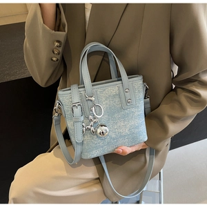 Detail of light blue bucket bag with silver balloon dog charm and adjustable strap