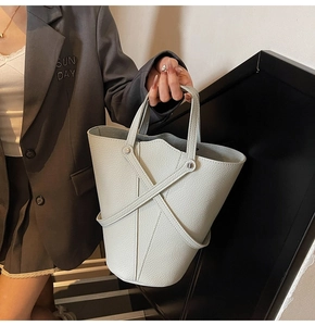 Detail of light grey pebbled leather bucket bag with crisscross decorative straps