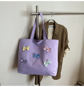 Detail of purple canvas tote bag with five colorful polka dot 3D bows on metallic hanger