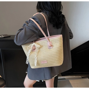Détail macro de la texture tissée beige et de l'anse en cuir rose d'un sac cabas en paille