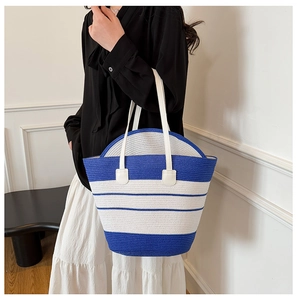 Détail d'un sac cabas tissé à rayures bleues et blanches avec de fines bretelles en cuir