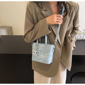 Blue mini bucket bag with silver balloon dog charm worn with an elegant blazer