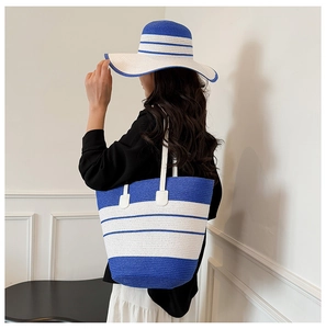 Détail d'un grand sac cabas en paille à rayures bleues et blanches avec chapeau assorti