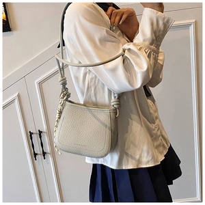 Close-up of light gray pebble leather texture and knotted strap detail on bucket bag