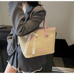 Détail du sac cabas en paille tissé avec anses en cuir rose et nœud en dentelle blanche