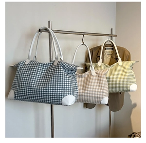 Detailed view of three houndstooth travel bags in blue, tan and green with leather handles