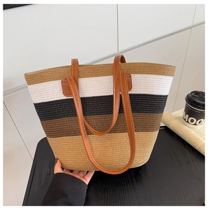 Detalle del bolso tote de paja tejida con rayas multicolores y asas de cuero marrón
