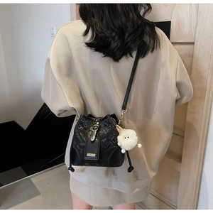 Close-up of black snake-pattern drawstring bucket bag with gold hardware and plush charm