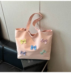 Detailed texture of pink canvas tote bag with five colorful polka dot bows on a sofa