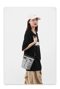Dettaglio borsa a tracolla in nylon grigio con texture a pieghe ed etichetta arancione