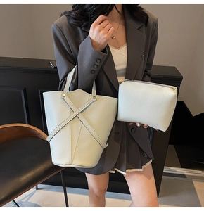 Detail view of beige leather bucket bag set with cross handles and pouch accessory