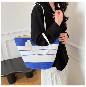 Gros plan d'un sac cabas tissé à rayures bleues et blanches avec fines bretelles blanches