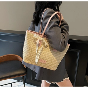 Détail du cabas en paille tissée avec bordure en cuir rose et élégant nœud en dentelle