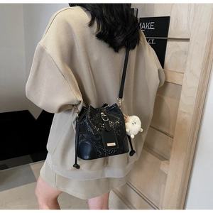 Detail of black snake embossed bucket bag with golden logo and white sheep plush charm