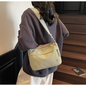 Detail of the nylon crossbody bag with zipper pocket and metal logo on adjustable wide strap